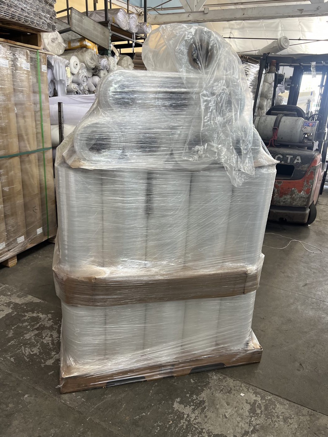 Pallet of goods wrapped and strapped in clear stretch film, staged for shipping